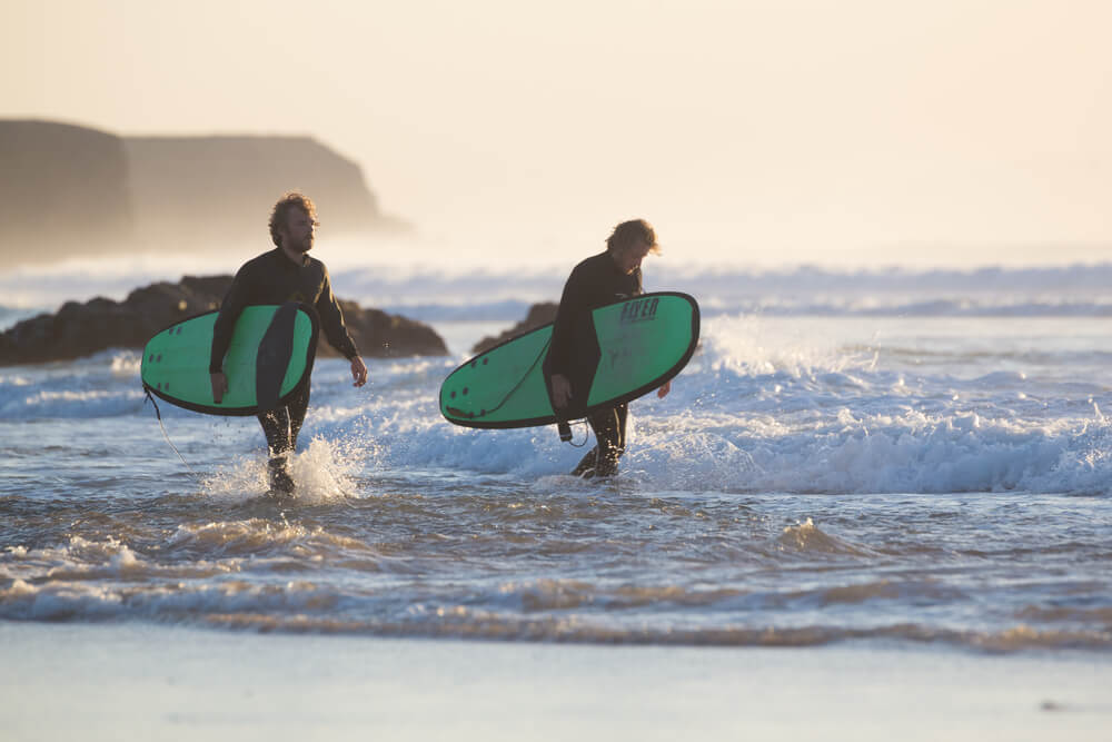 Due surfisti camminano lungo la spiaggia di El Cotillo, famosa destinazione per il surf a Fuerteventura